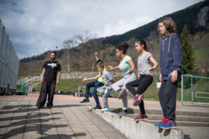 Kinder balancieren draussen auf Mauer im Sportlager Fiesch