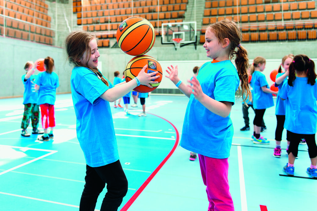 Mädchen in einer Turnhalle mit Basketbällen
