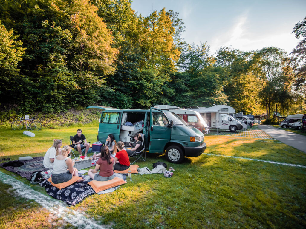 Van und eine Gruppe auf einer Picknickdecke auf dem Camping Eichholz