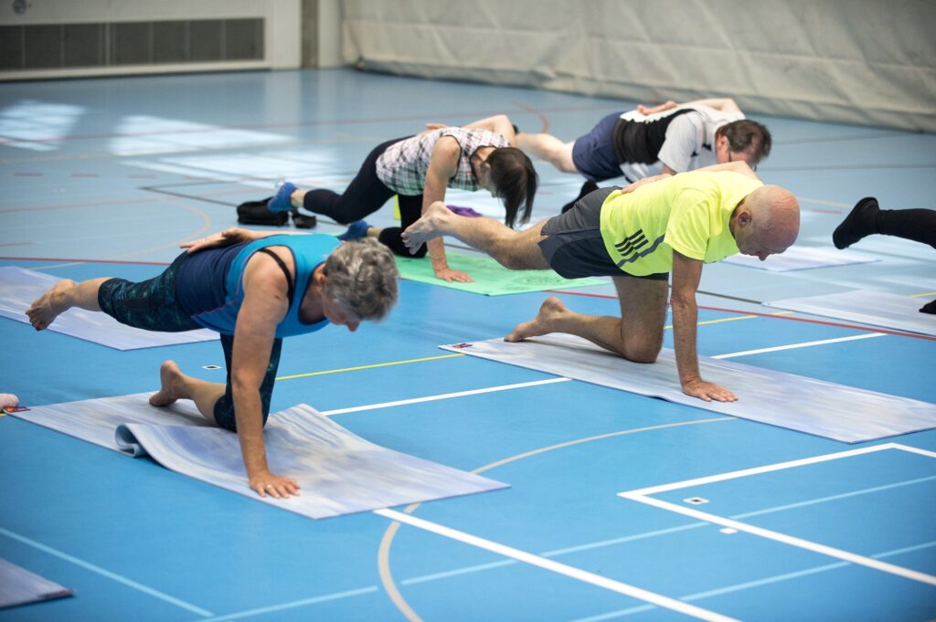 Frauen und Männer machen Übungen am Boden während der AktivPLUS Sportwoche